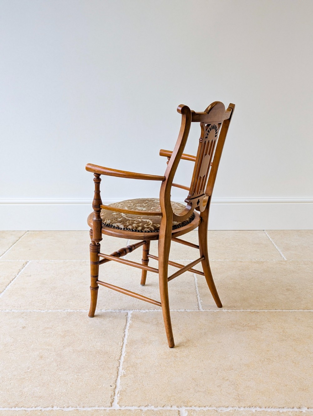 A late Victorian satinwood elbow chair featuring a lyre-shaped backrest with a painted central medallion, turned front legs, and an upholstered seat. View XVII