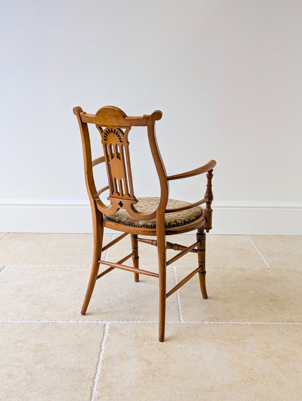 A late Victorian satinwood elbow chair featuring a lyre-shaped backrest with a painted central medallion, turned front legs, and an upholstered seat. View XVIII