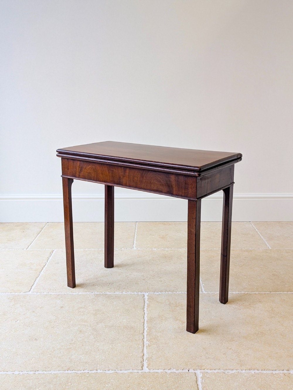 A Regency mahogany flip-top card table with square legs and a flame mahogany frieze.