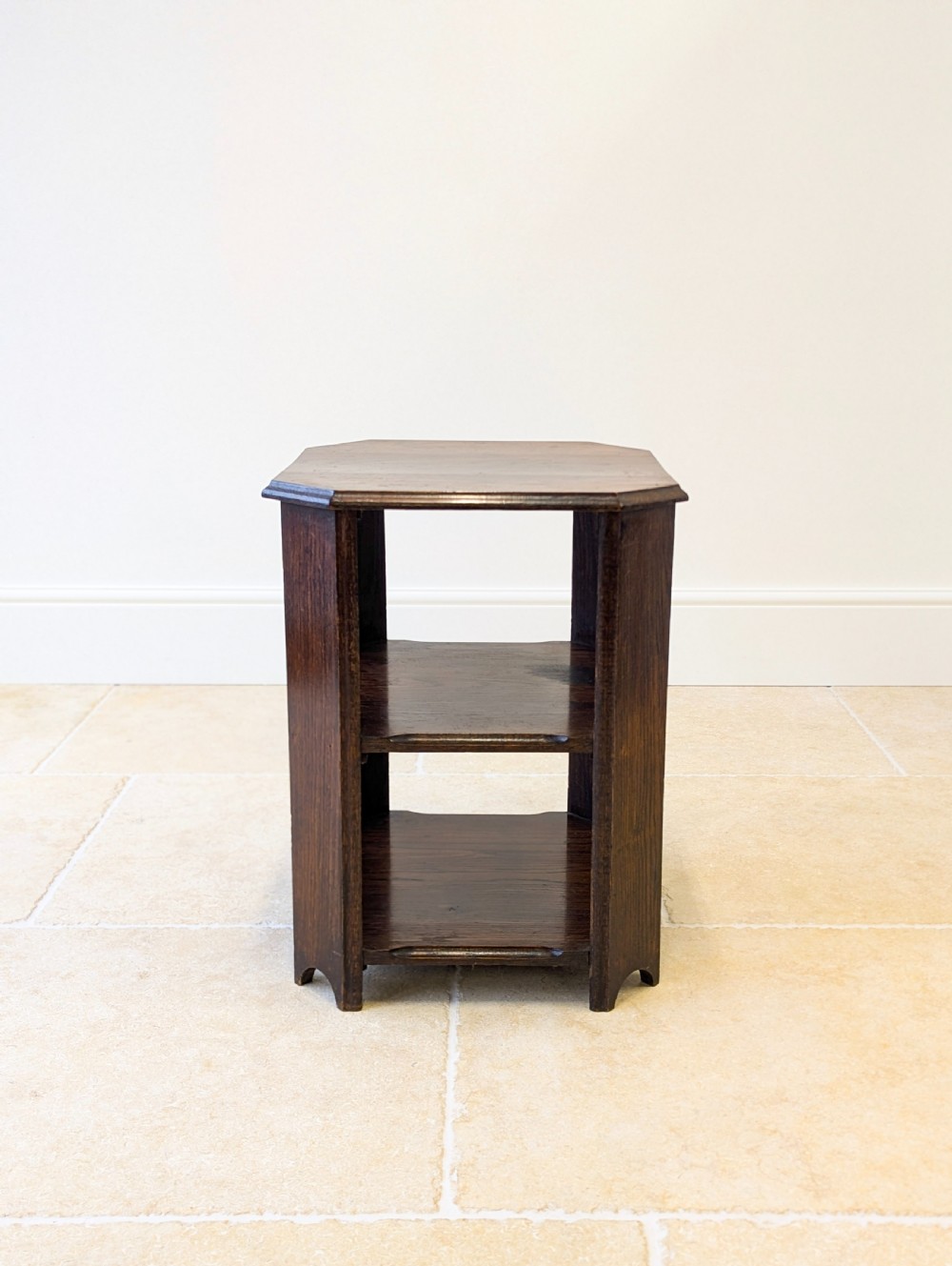 A dark brown oak book table with clipped corners on top and two open lower shelves supported by straight side legs. View III