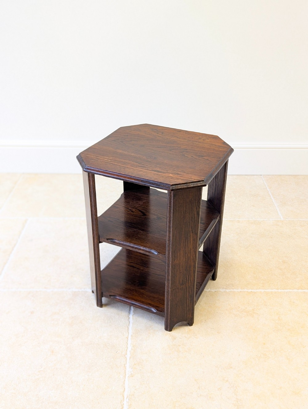 A dark brown oak book table with clipped corners on top and two open lower shelves supported by straight side legs. View V