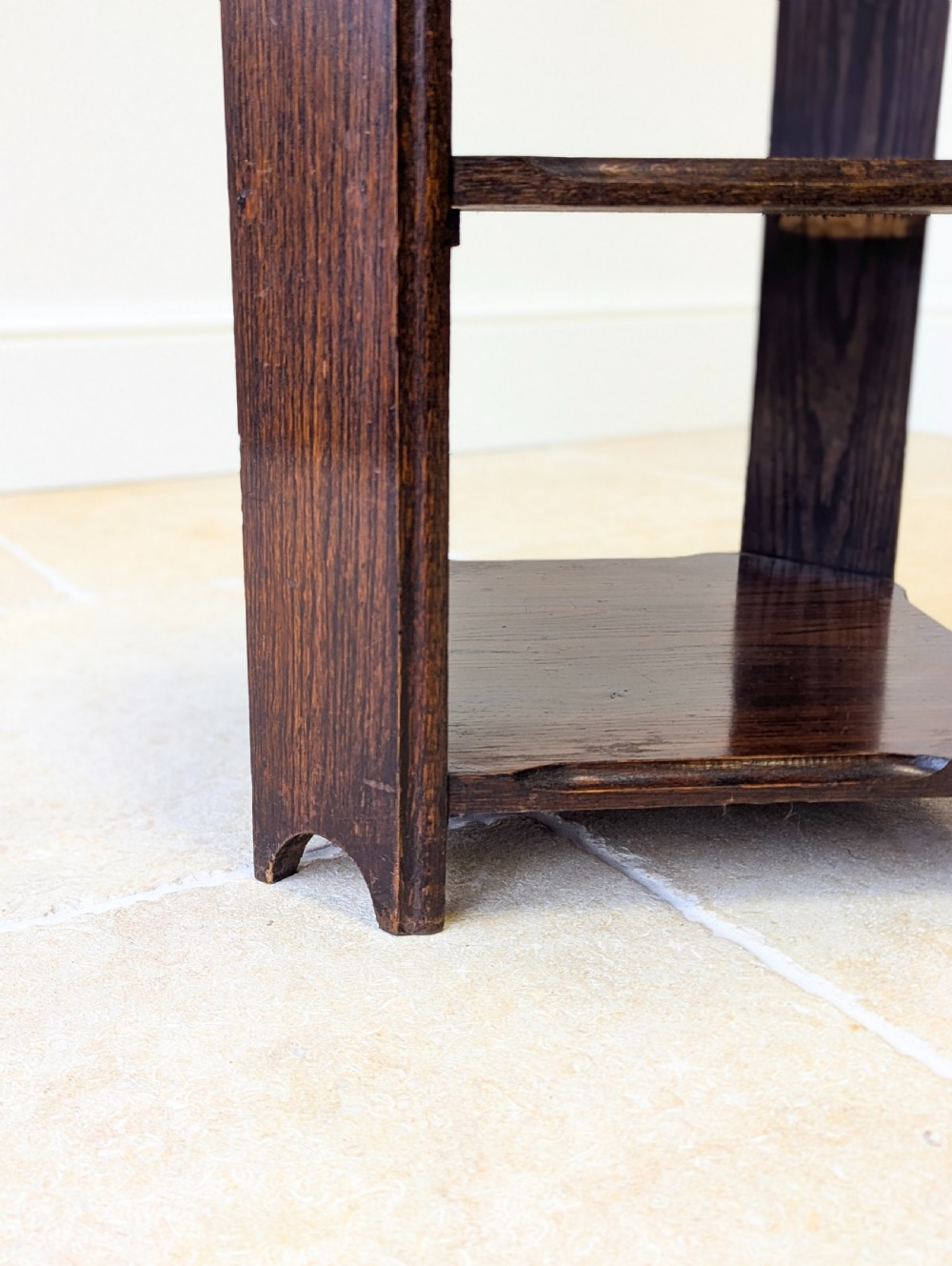 A dark brown oak book table with clipped corners on top and two open lower shelves supported by straight side legs. View VI