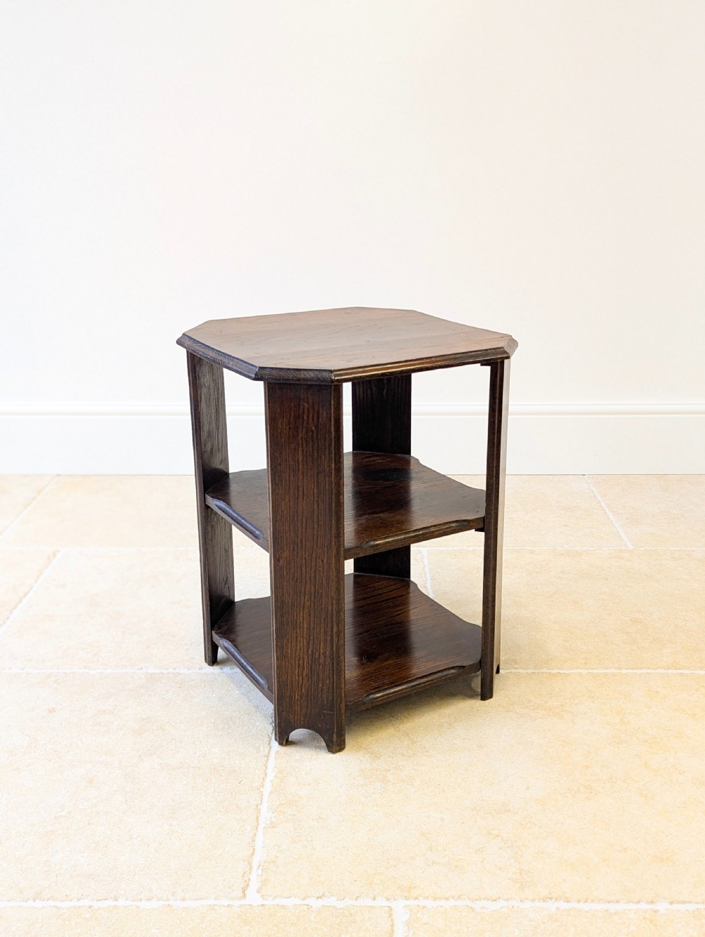 A dark brown oak book table with clipped corners on top and two open lower shelves supported by straight side legs. View VII