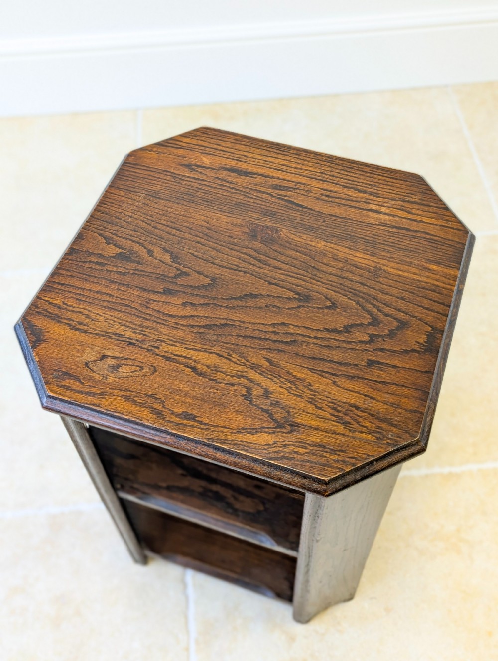 A dark brown oak book table with clipped corners on top and two open lower shelves supported by straight side legs. View IX