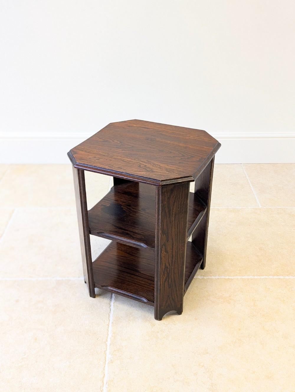 A dark brown oak book table with clipped corners on top and two open lower shelves supported by straight side legs. View X