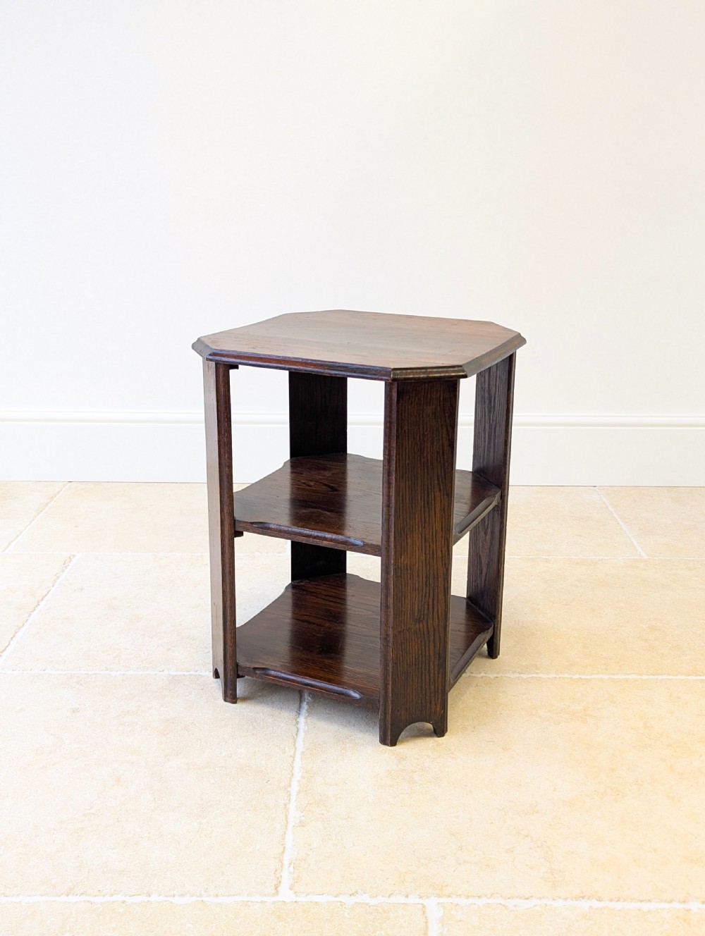 A dark brown oak book table with clipped corners on top and two open lower shelves supported by straight side legs. View XII