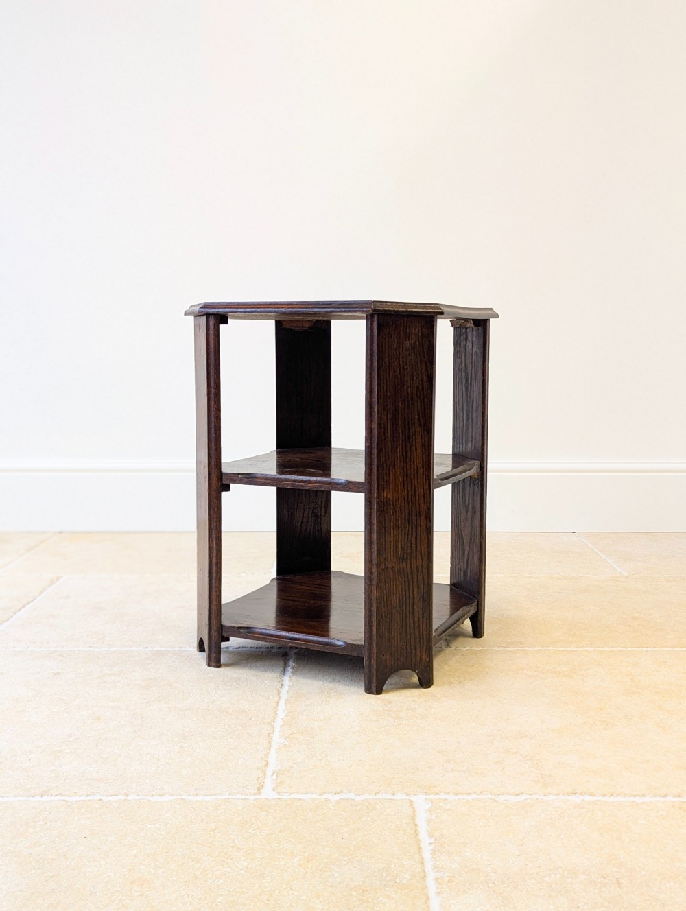 A dark brown oak book table with clipped corners on top and two open lower shelves supported by straight side legs. View XIV