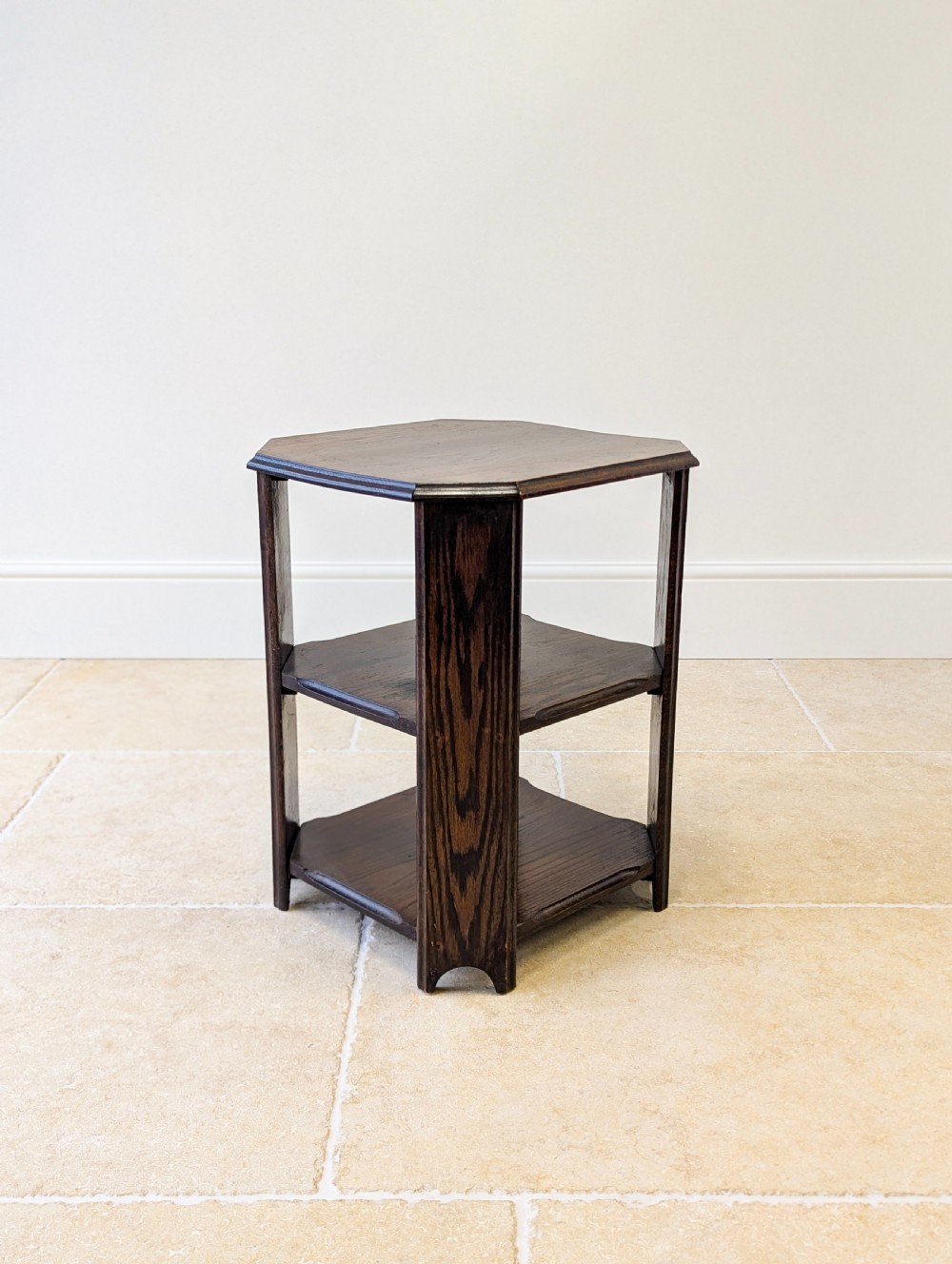 A dark brown oak book table with clipped corners on top and two open lower shelves supported by straight side legs. View XV