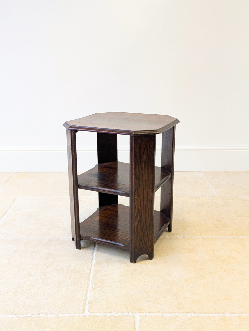 A dark brown oak book table with clipped corners on top and two open lower shelves supported by straight side legs. View XVI