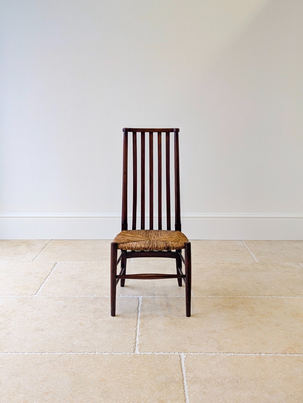 An Arts and Crafts dark mahogany side chair featuring a tall vertical slat backrest, a woven rush seat, and simple turned legs with stretchers. View II
