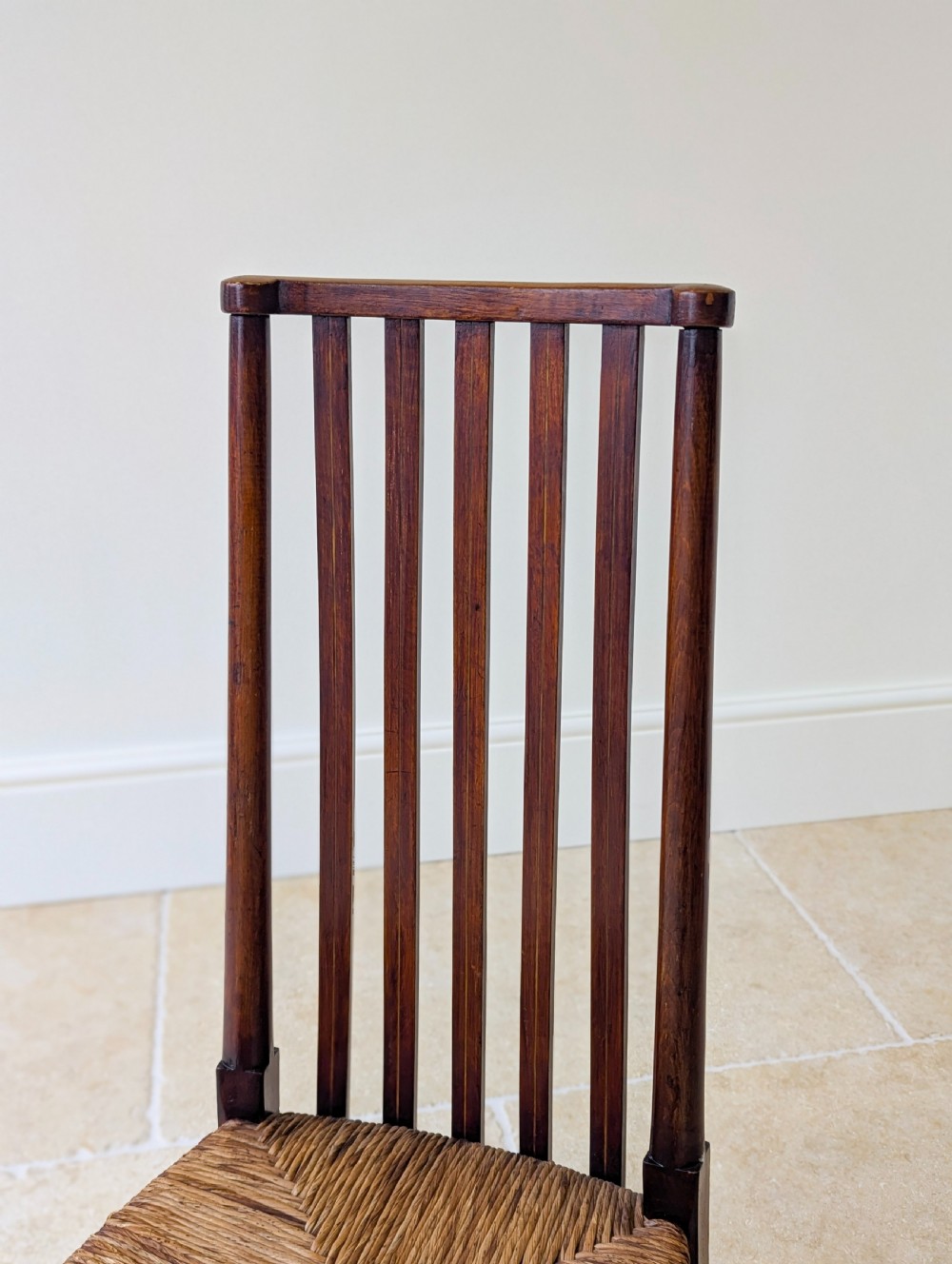 An Arts and Crafts dark mahogany side chair featuring a tall vertical slat backrest, a woven rush seat, and simple turned legs with stretchers. View IV