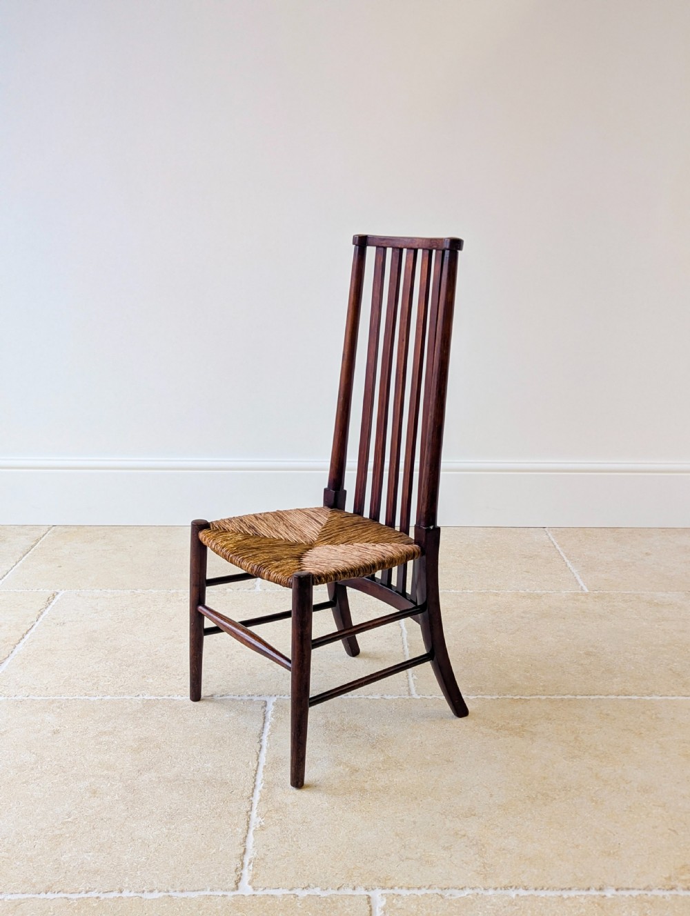 An Arts and Crafts dark mahogany side chair featuring a tall vertical slat backrest, a woven rush seat, and simple turned legs with stretchers. View IX
