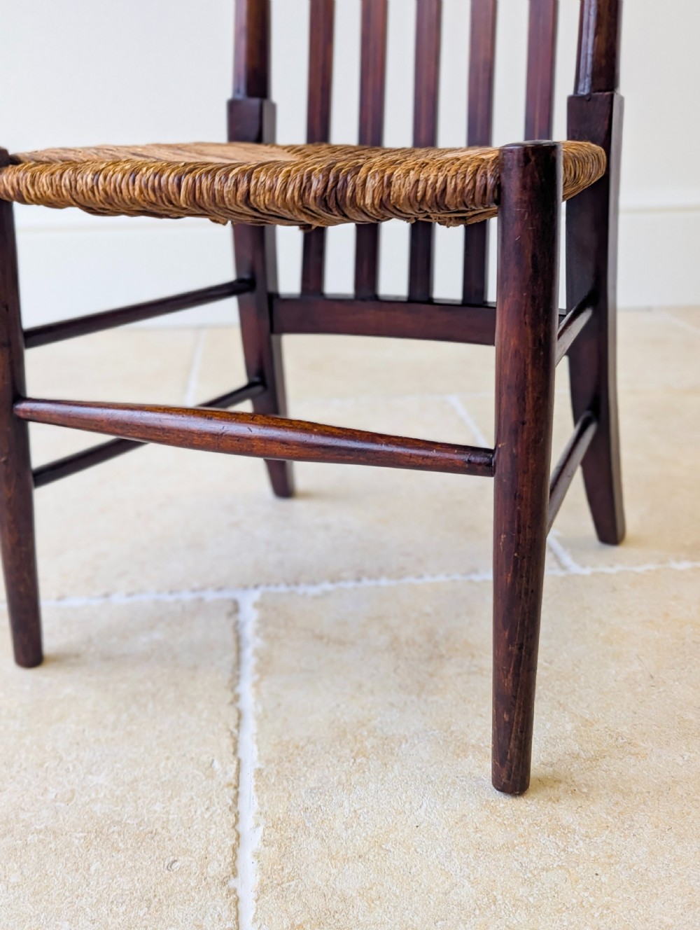 An Arts and Crafts dark mahogany side chair featuring a tall vertical slat backrest, a woven rush seat, and simple turned legs with stretchers. View XI