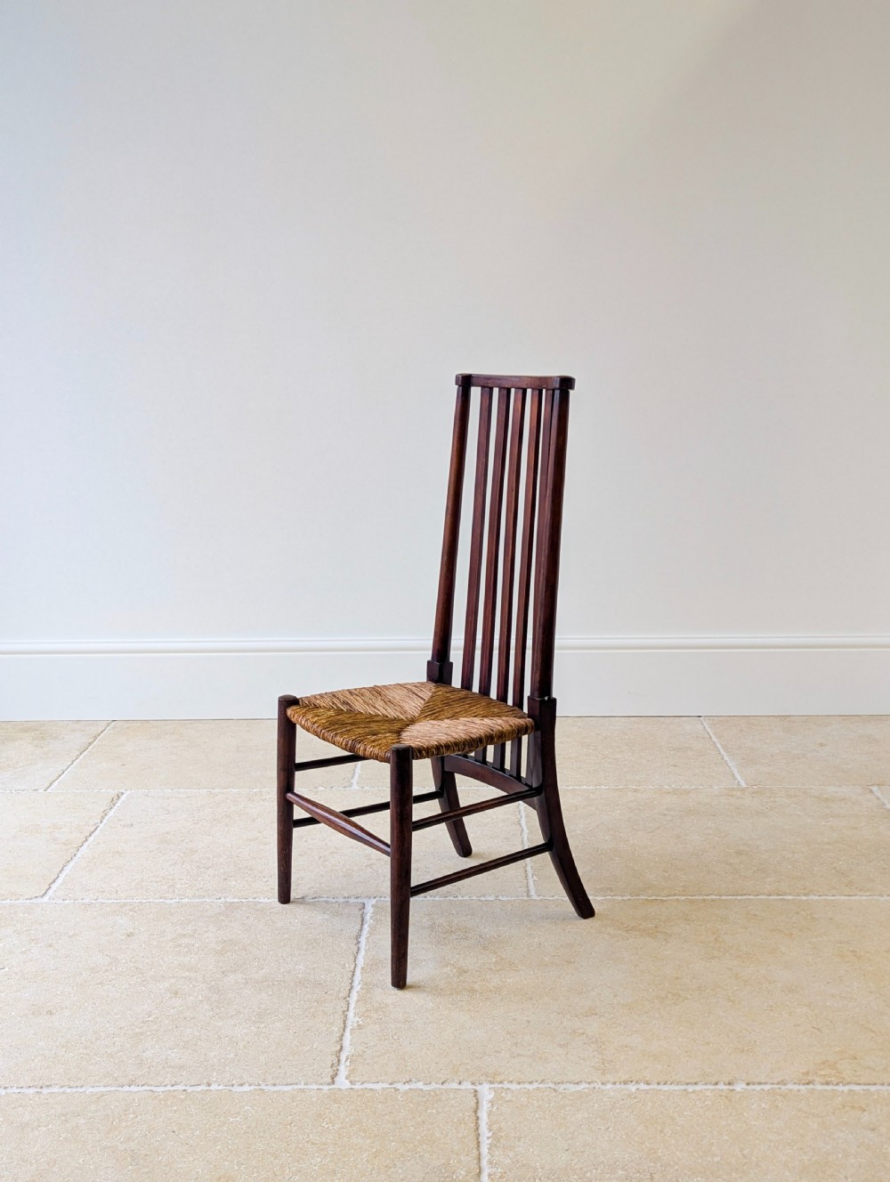 An Arts and Crafts dark mahogany side chair featuring a tall vertical slat backrest, a woven rush seat, and simple turned legs with stretchers. View XII