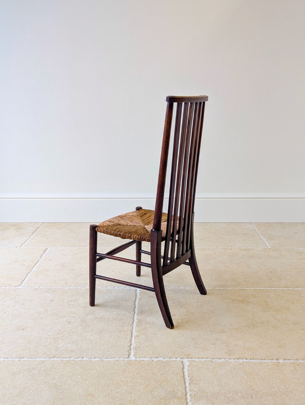 An Arts and Crafts dark mahogany side chair featuring a tall vertical slat backrest, a woven rush seat, and simple turned legs with stretchers. View XIV