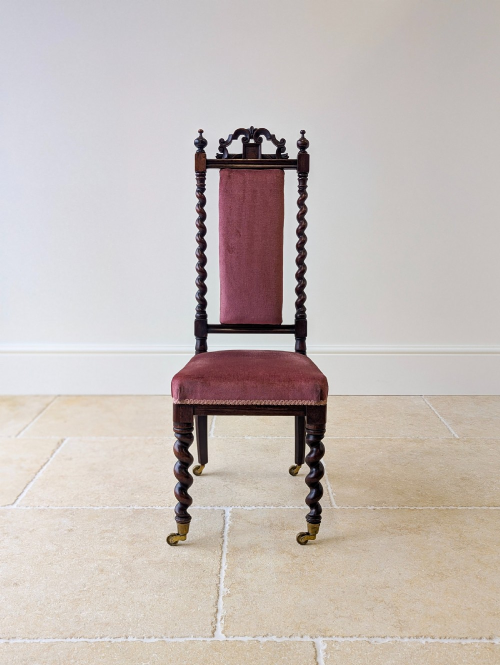 A Victorian rosewood side chair featuring barley twist legs and uprights, a carved cresting rail, dusty pink velvet upholstery, and brass castors. View II