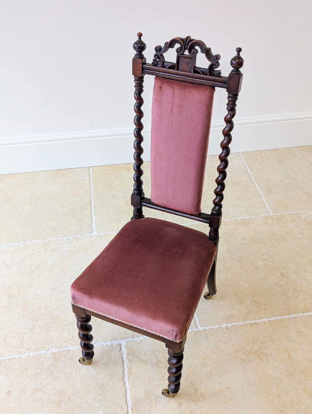 A Victorian rosewood side chair featuring barley twist legs and uprights, a carved cresting rail, dusty pink velvet upholstery, and brass castors. View III
