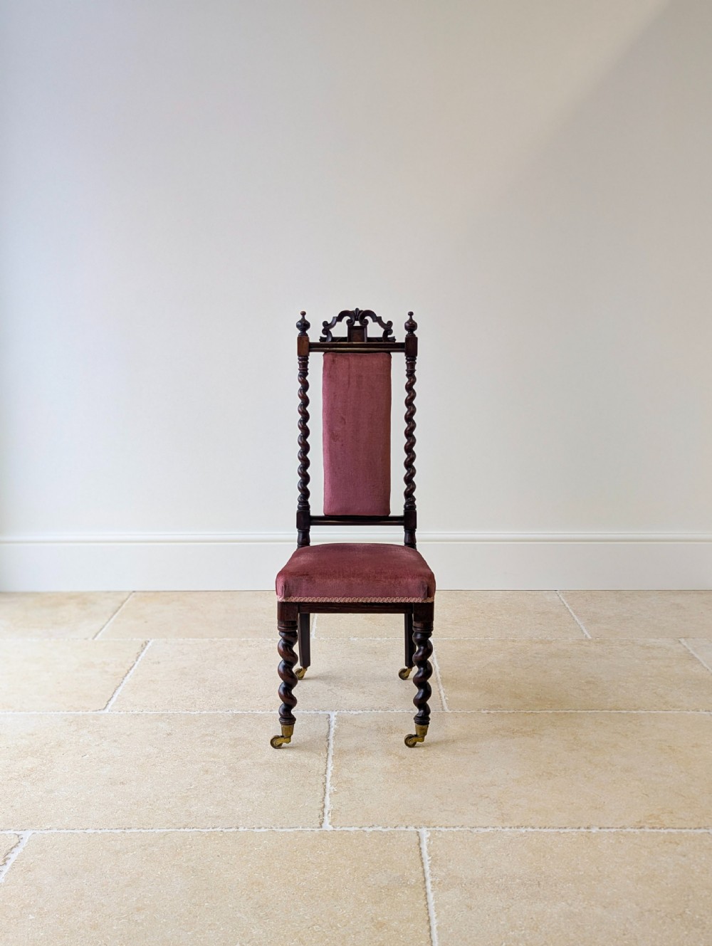 A Victorian rosewood side chair featuring barley twist legs and uprights, a carved cresting rail, dusty pink velvet upholstery, and brass castors. View IX