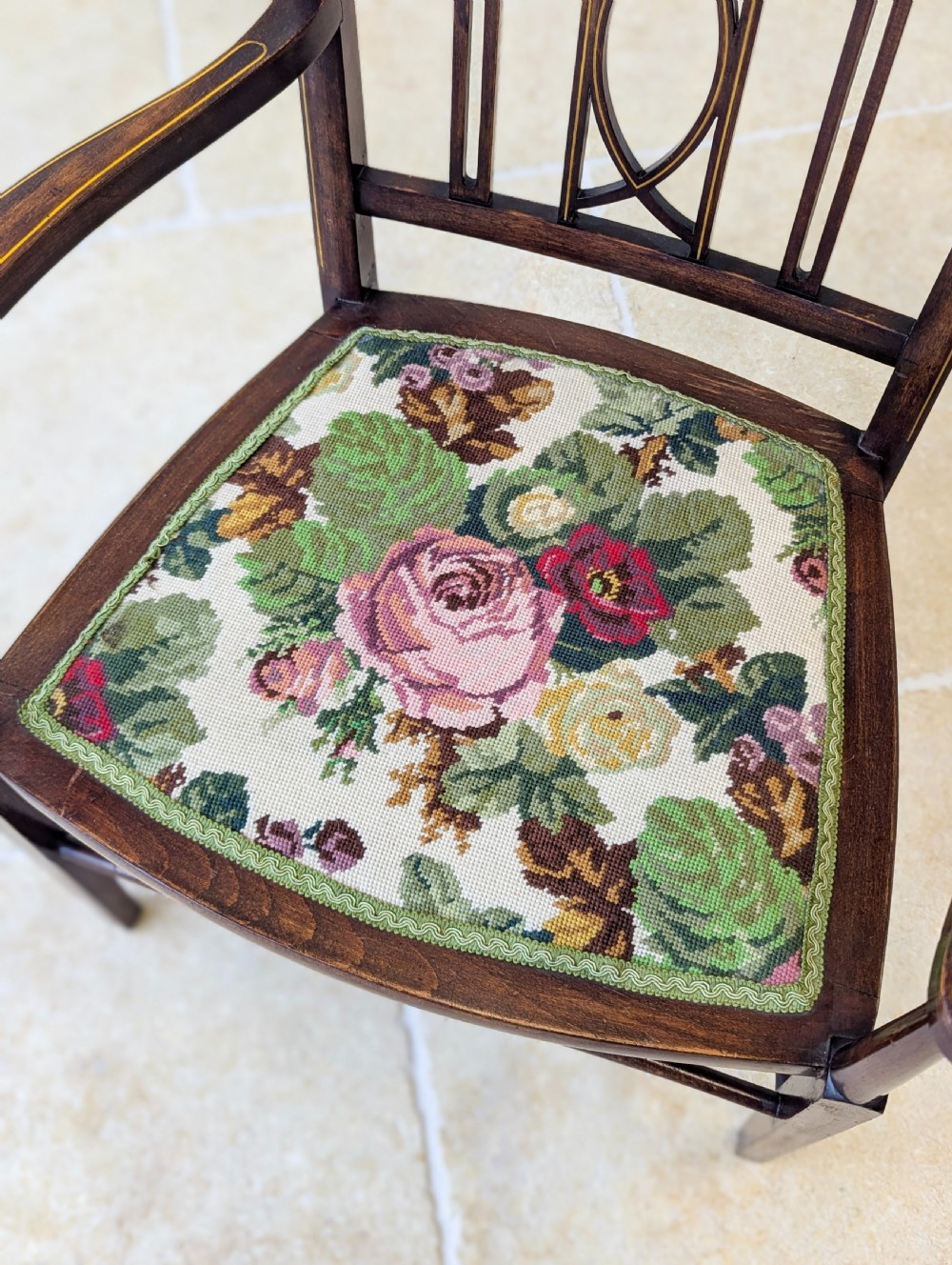 An Edwardian dark mahogany elbow chair featuring a tall pierced splat back, sloped armrests, straight legs with stretchers, and a floral tapestry seat. View IV