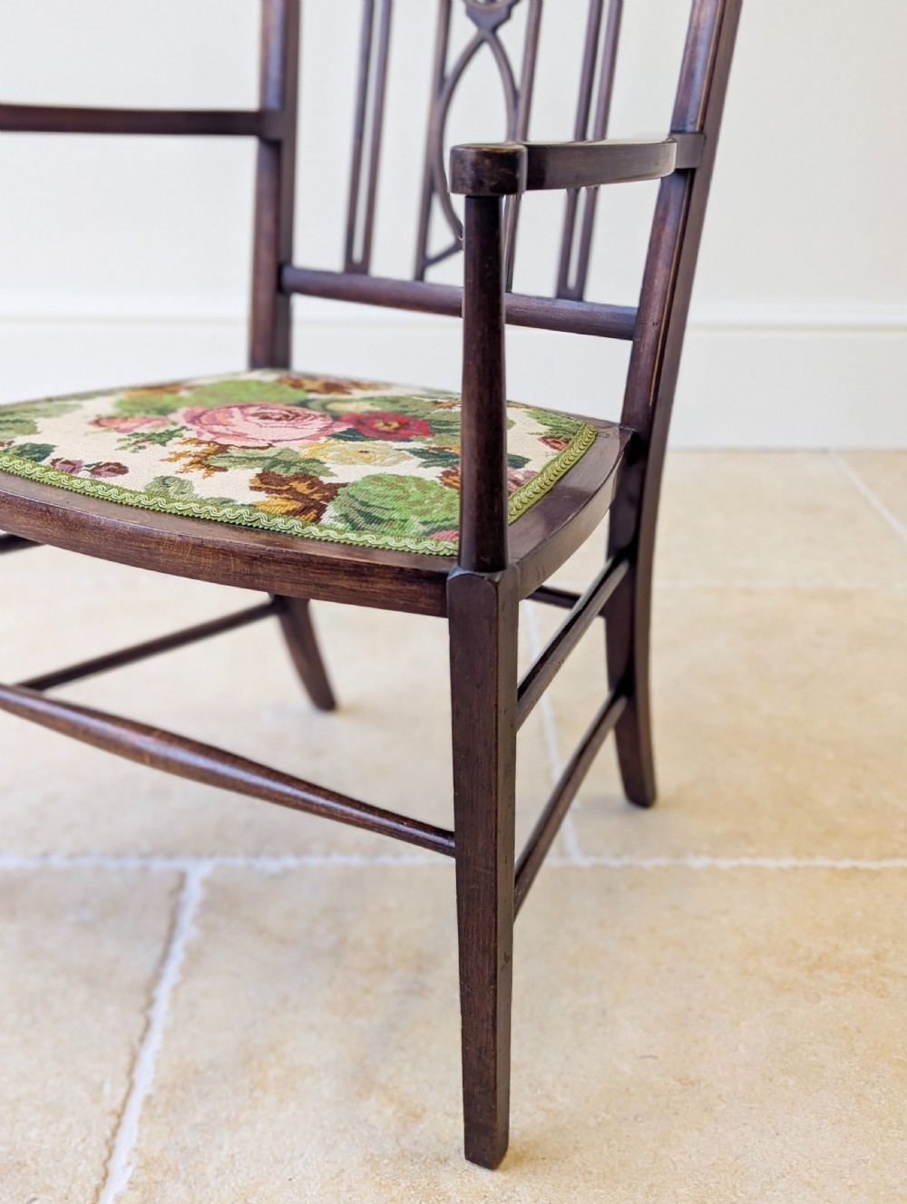 An Edwardian dark mahogany elbow chair featuring a tall pierced splat back, sloped armrests, straight legs with stretchers, and a floral tapestry seat. View X