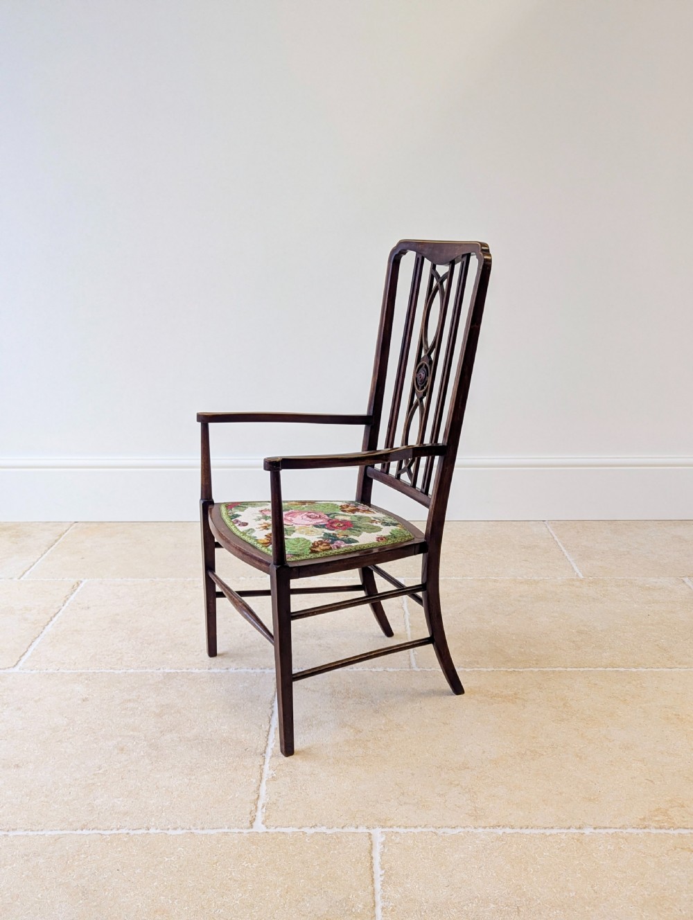 An Edwardian dark mahogany elbow chair featuring a tall pierced splat back, sloped armrests, straight legs with stretchers, and a floral tapestry seat. View XI