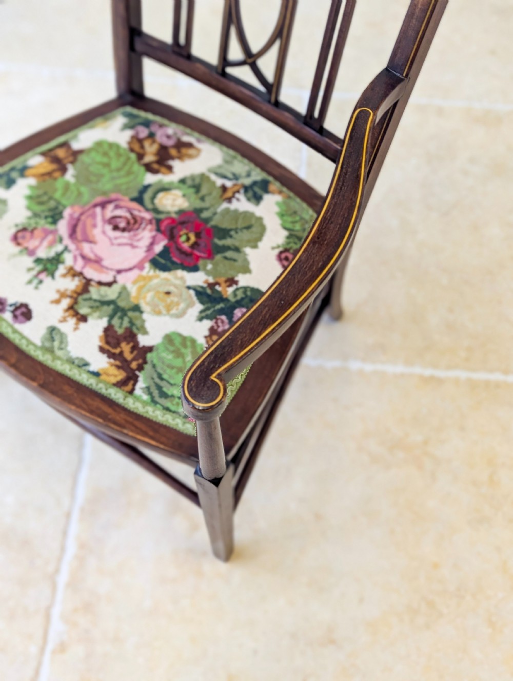 An Edwardian dark mahogany elbow chair featuring a tall pierced splat back, sloped armrests, straight legs with stretchers, and a floral tapestry seat. View XII