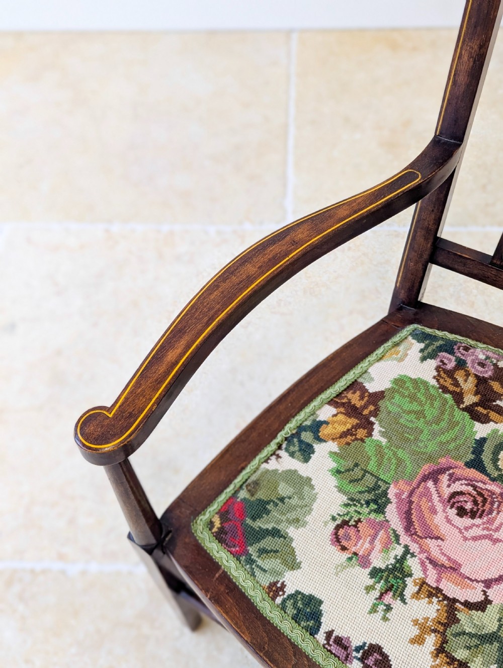 An Edwardian dark mahogany elbow chair featuring a tall pierced splat back, sloped armrests, straight legs with stretchers, and a floral tapestry seat. View XIV