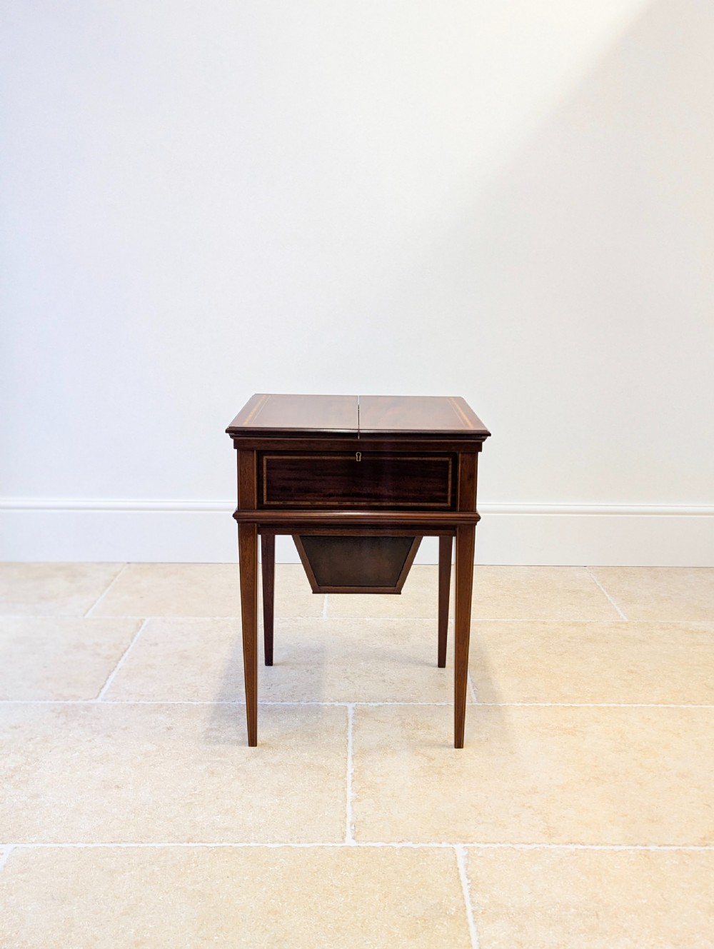 An Edwardian dark mahogany metamorphic writing table featuring two hinged side flaps, a sloped leather writing surface, integrated stationery dividers, and tapered legs. View II