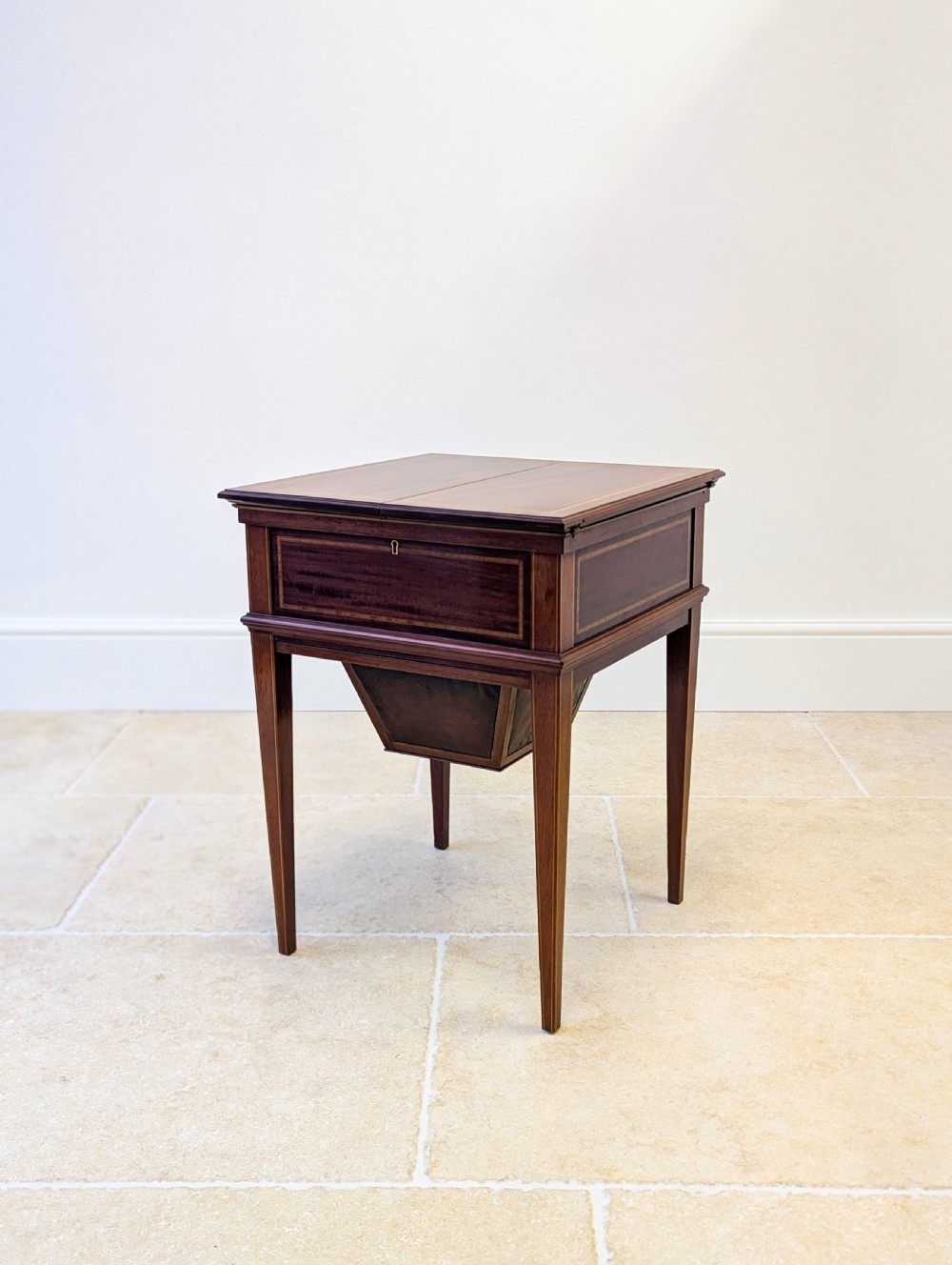 An Edwardian dark mahogany metamorphic writing table featuring two hinged side flaps, a sloped leather writing surface, integrated stationery dividers, and tapered legs. View VI
