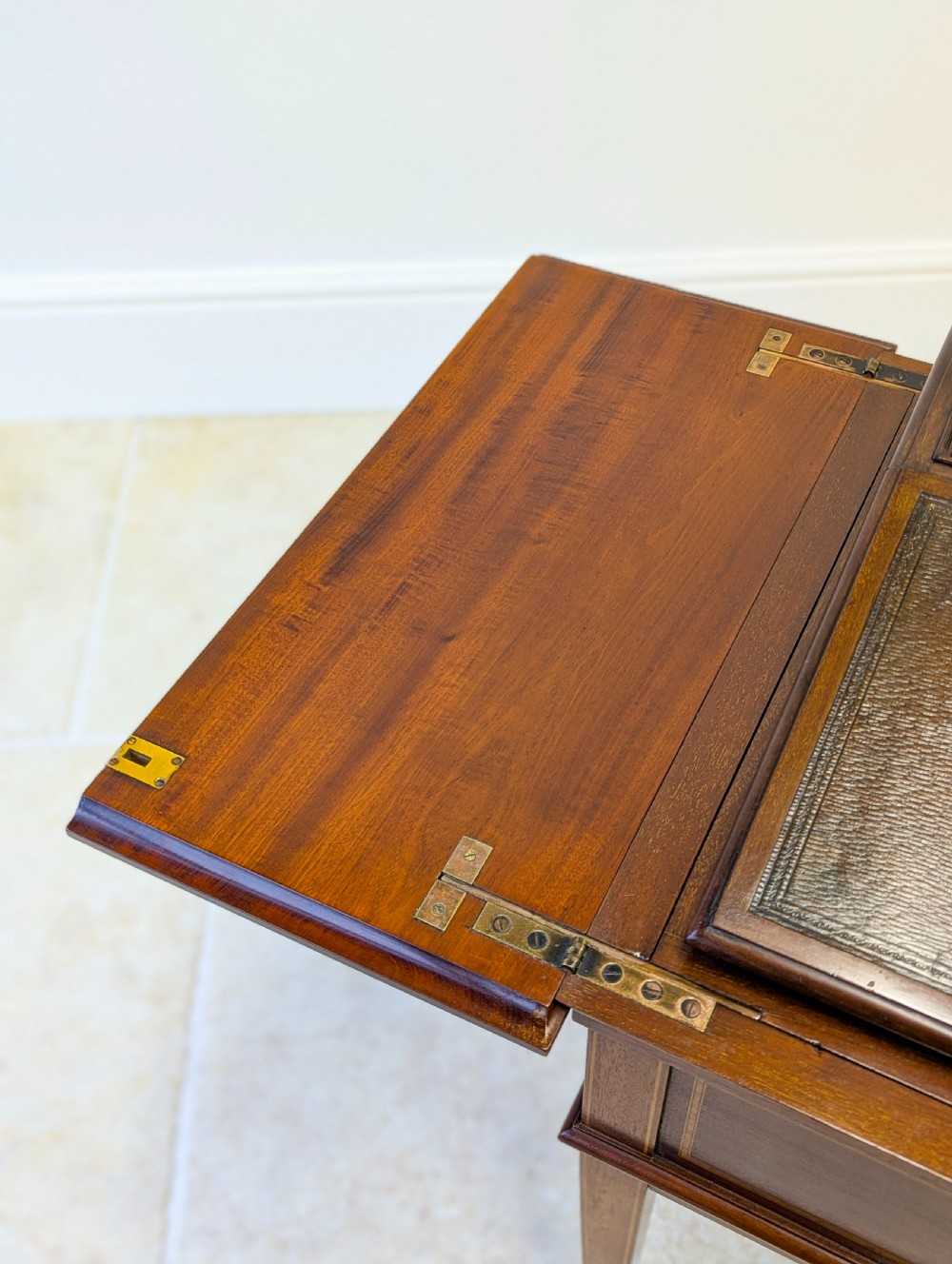 An Edwardian dark mahogany metamorphic writing table featuring two hinged side flaps, a sloped leather writing surface, integrated stationery dividers, and tapered legs. View XI