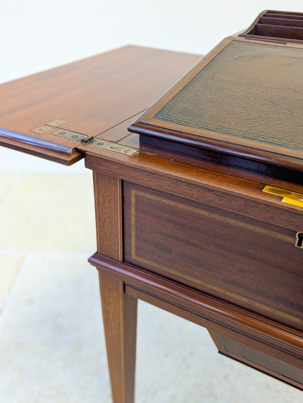 An Edwardian dark mahogany metamorphic writing table featuring two hinged side flaps, a sloped leather writing surface, integrated stationery dividers, and tapered legs. View XIII