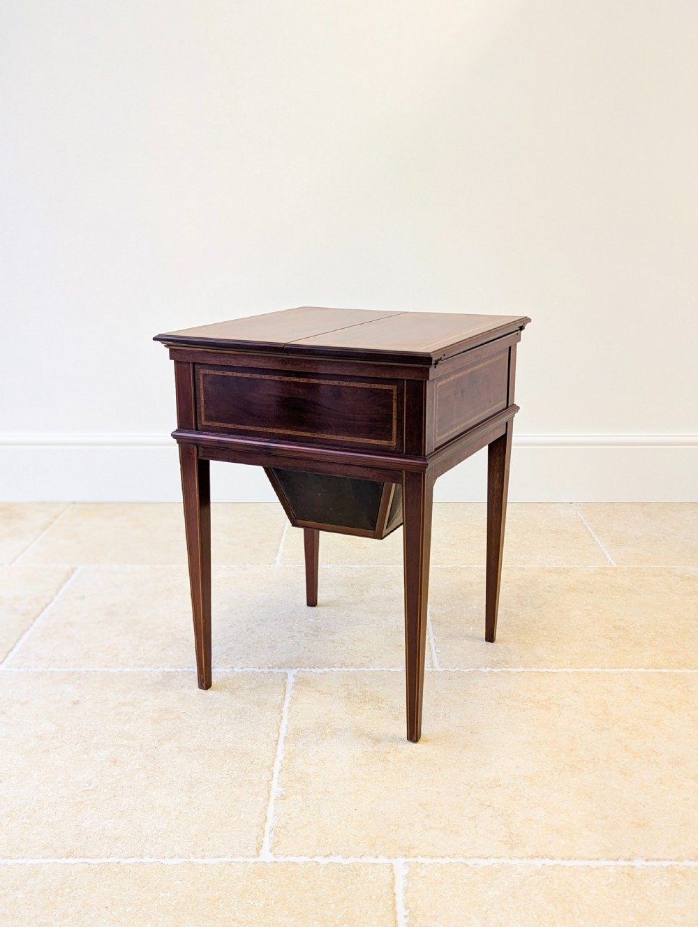 An Edwardian dark mahogany metamorphic writing table featuring two hinged side flaps, a sloped leather writing surface, integrated stationery dividers, and tapered legs. View XIX