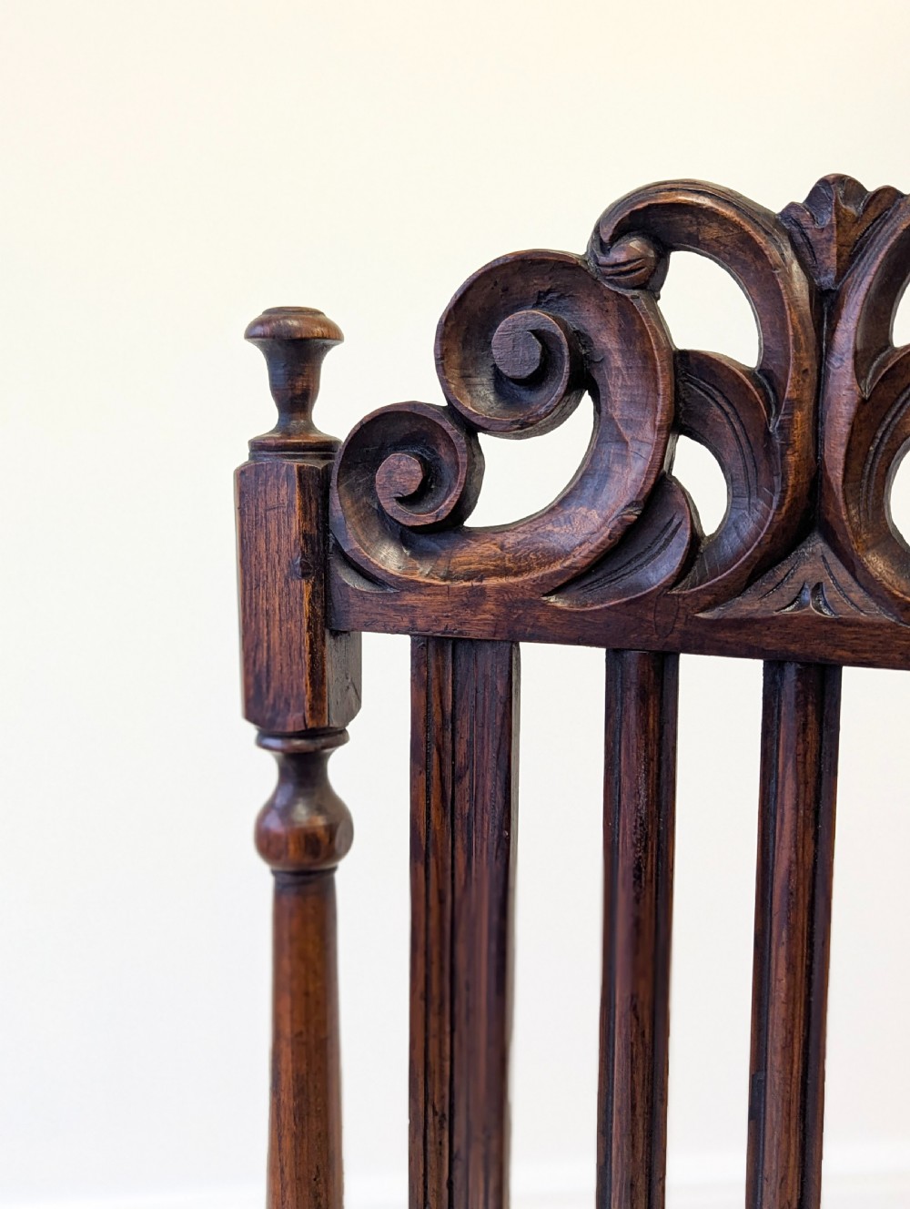 A dark oak William and Mary armchair featuring a carved scrollwork cresting rail, vertical back splats, open arms, and turned legs with stretchers. View VII