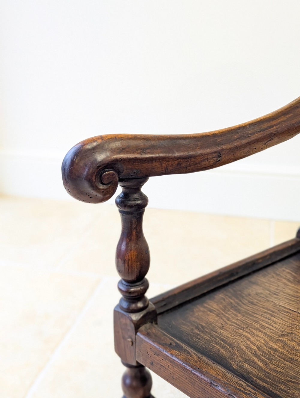 A dark oak William and Mary armchair featuring a carved scrollwork cresting rail, vertical back splats, open arms, and turned legs with stretchers. View IX