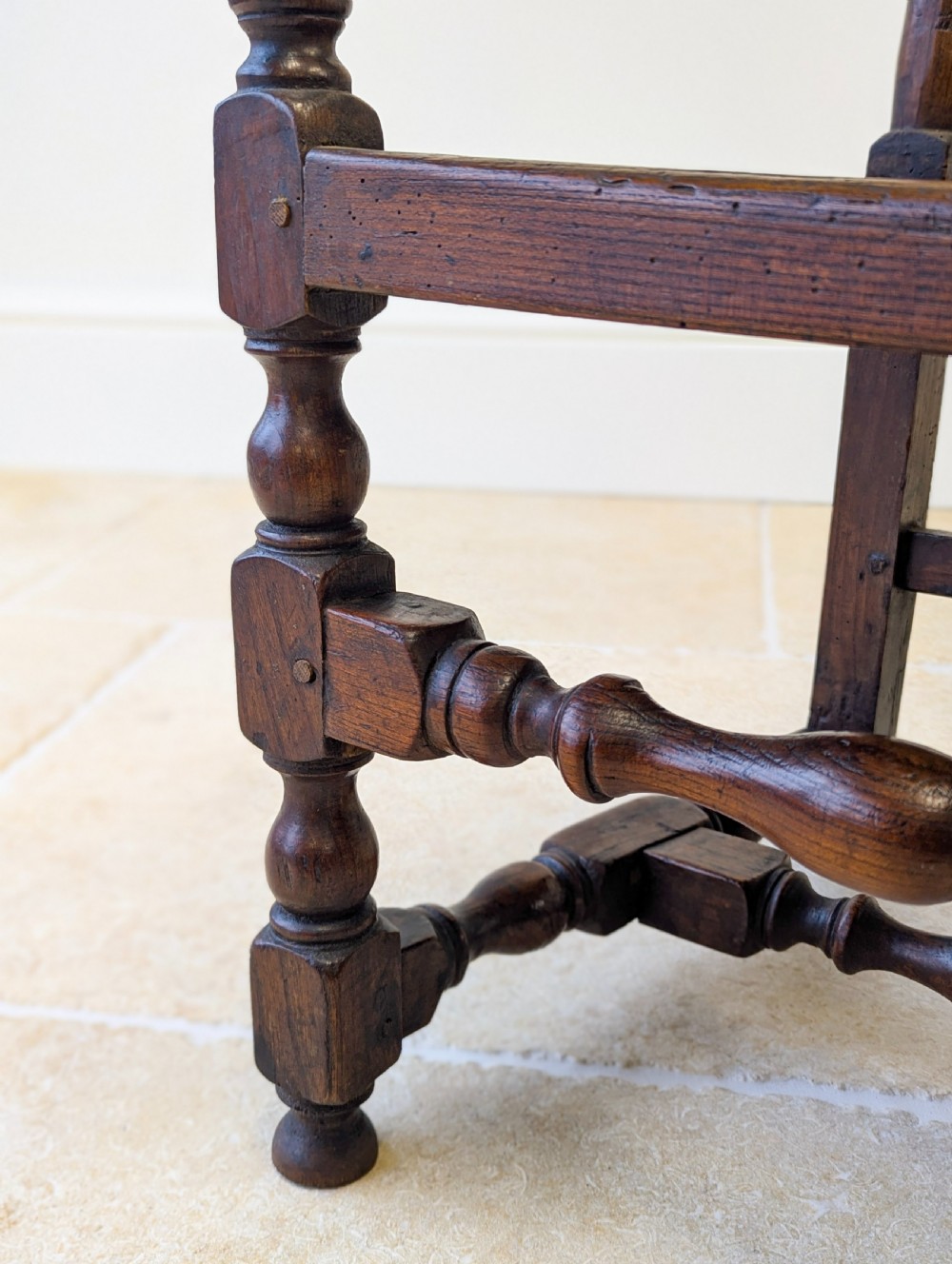 A dark oak William and Mary armchair featuring a carved scrollwork cresting rail, vertical back splats, open arms, and turned legs with stretchers. View XI