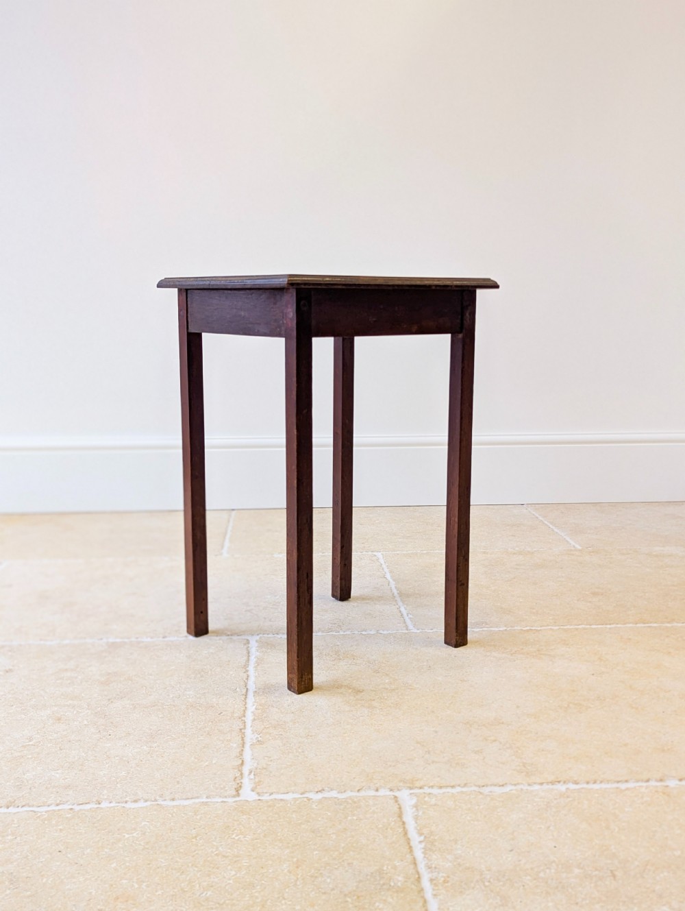 A square dark oak occasional table featuring a relief-carved floral border around a central circular panel, supported by four straight square legs. View VII