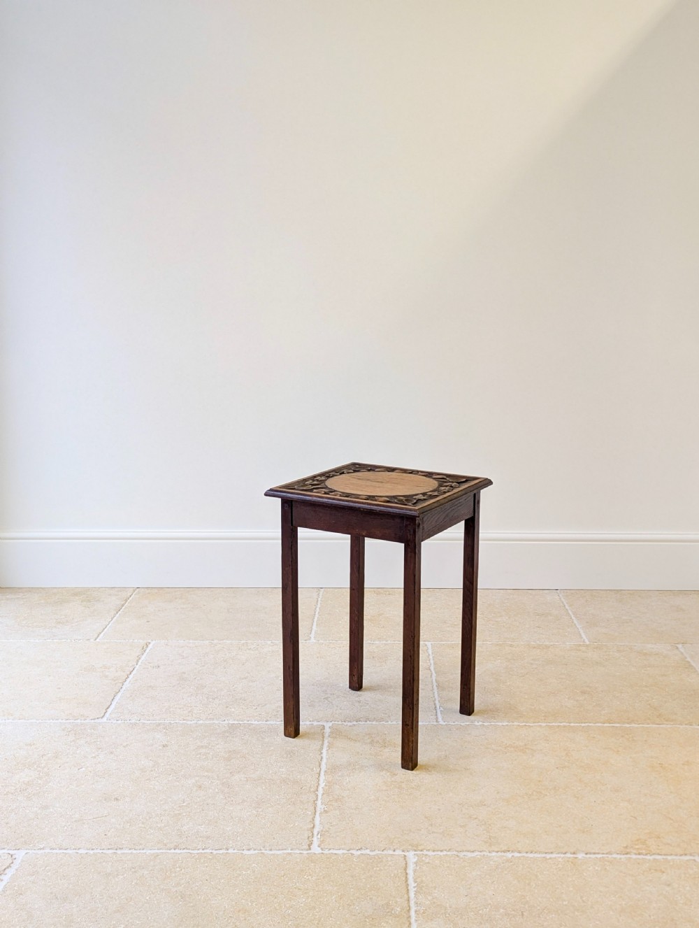 A square dark oak occasional table featuring a relief-carved floral border around a central circular panel, supported by four straight square legs. View XIII