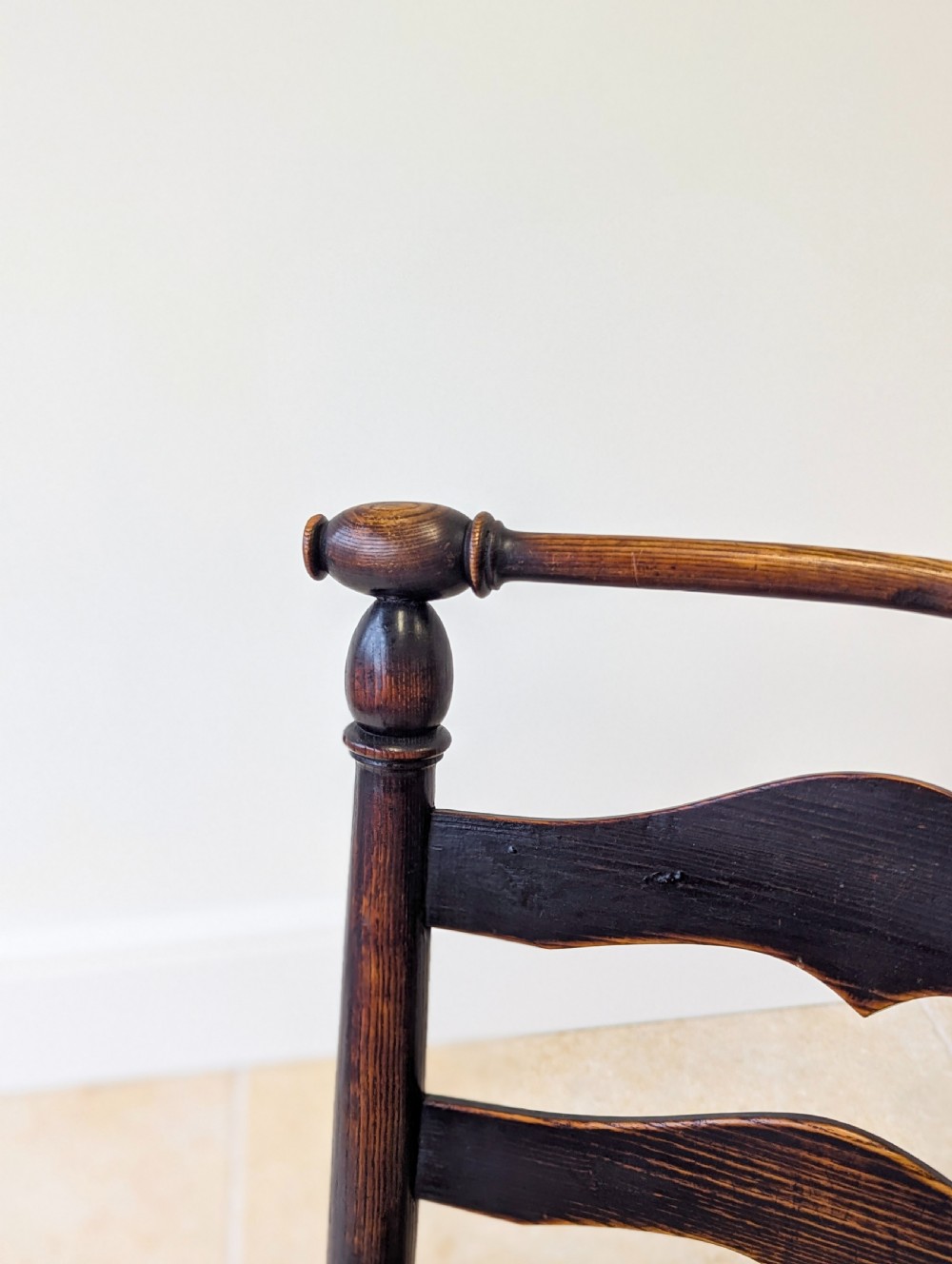 A late nineteenth-century country ash armchair featuring a ladderback design with four curved horizontal slats, turned armrest supports, and a hand-woven natural rush seat. View X