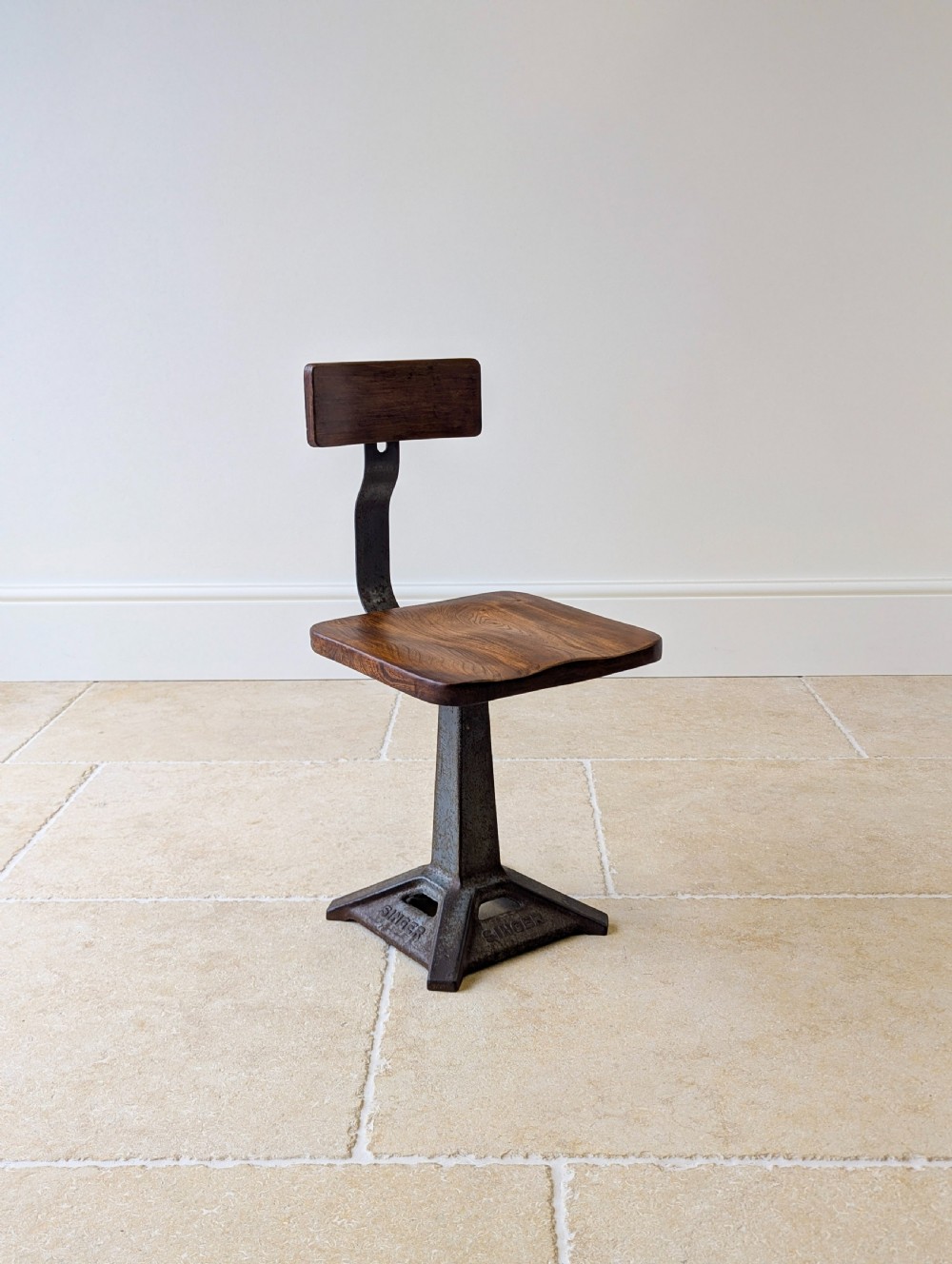 An early 20th-century Singer industrial chair featuring a dark cast iron pedestal base, a threaded height-adjustment mechanism, and a shaped elm seat with an attached wooden backrest. View III