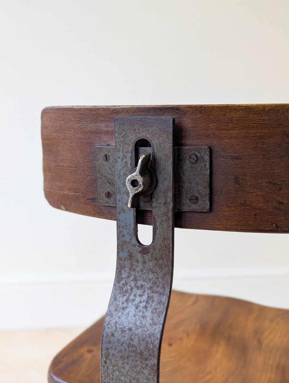 An early 20th-century Singer industrial chair featuring a dark cast iron pedestal base, a threaded height-adjustment mechanism, and a shaped elm seat with an attached wooden backrest. View VI