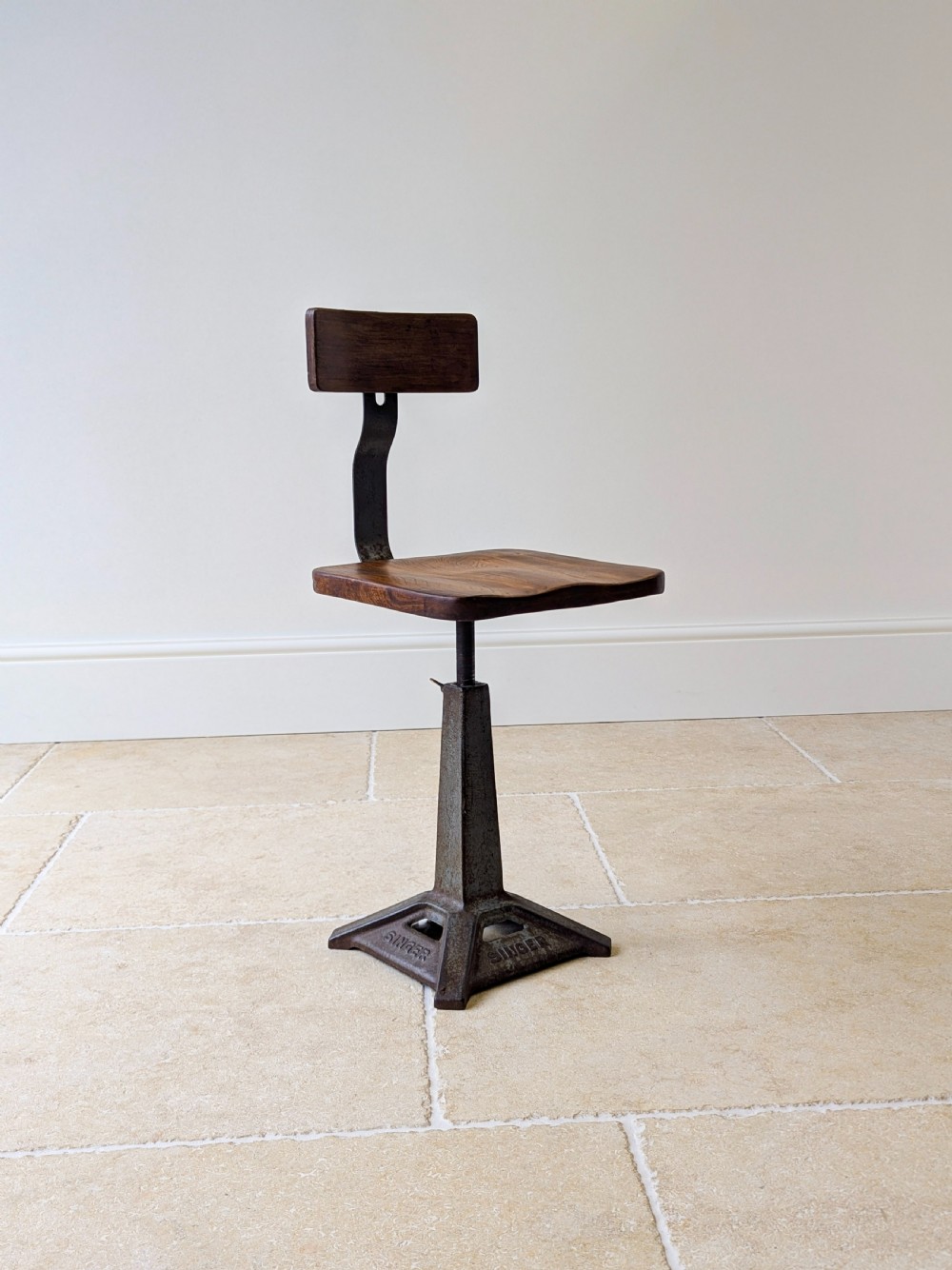 An early 20th-century Singer industrial chair featuring a dark cast iron pedestal base, a threaded height-adjustment mechanism, and a shaped elm seat with an attached wooden backrest. View XIII