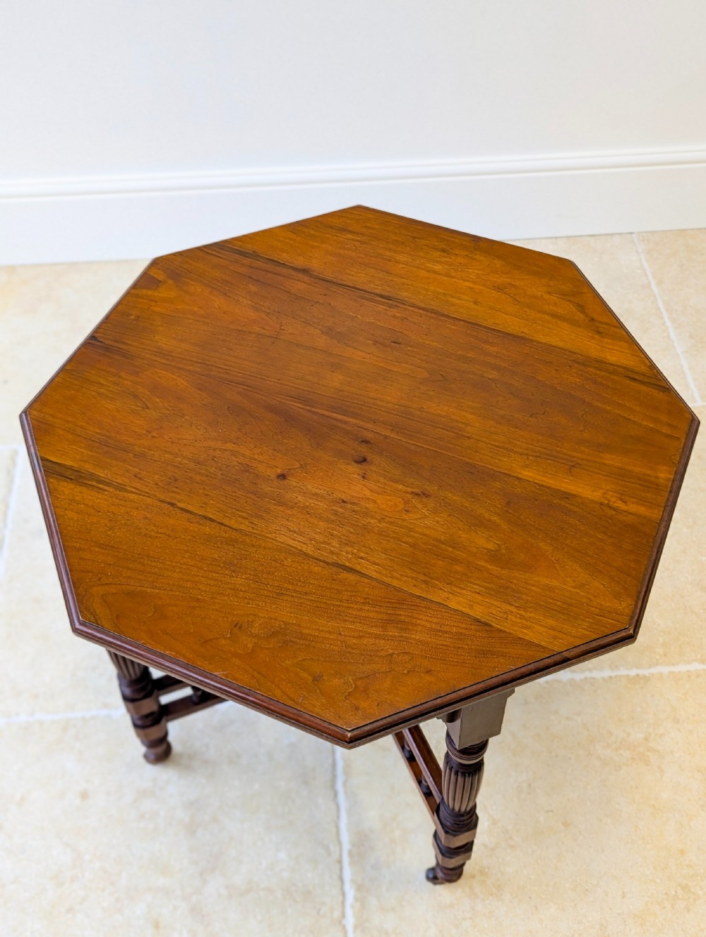 A late Victorian mahogany octagonal centre table featuring turned reeded legs, an intricate X-stretcher with baluster spindles, a central finial, and brass castors. View III