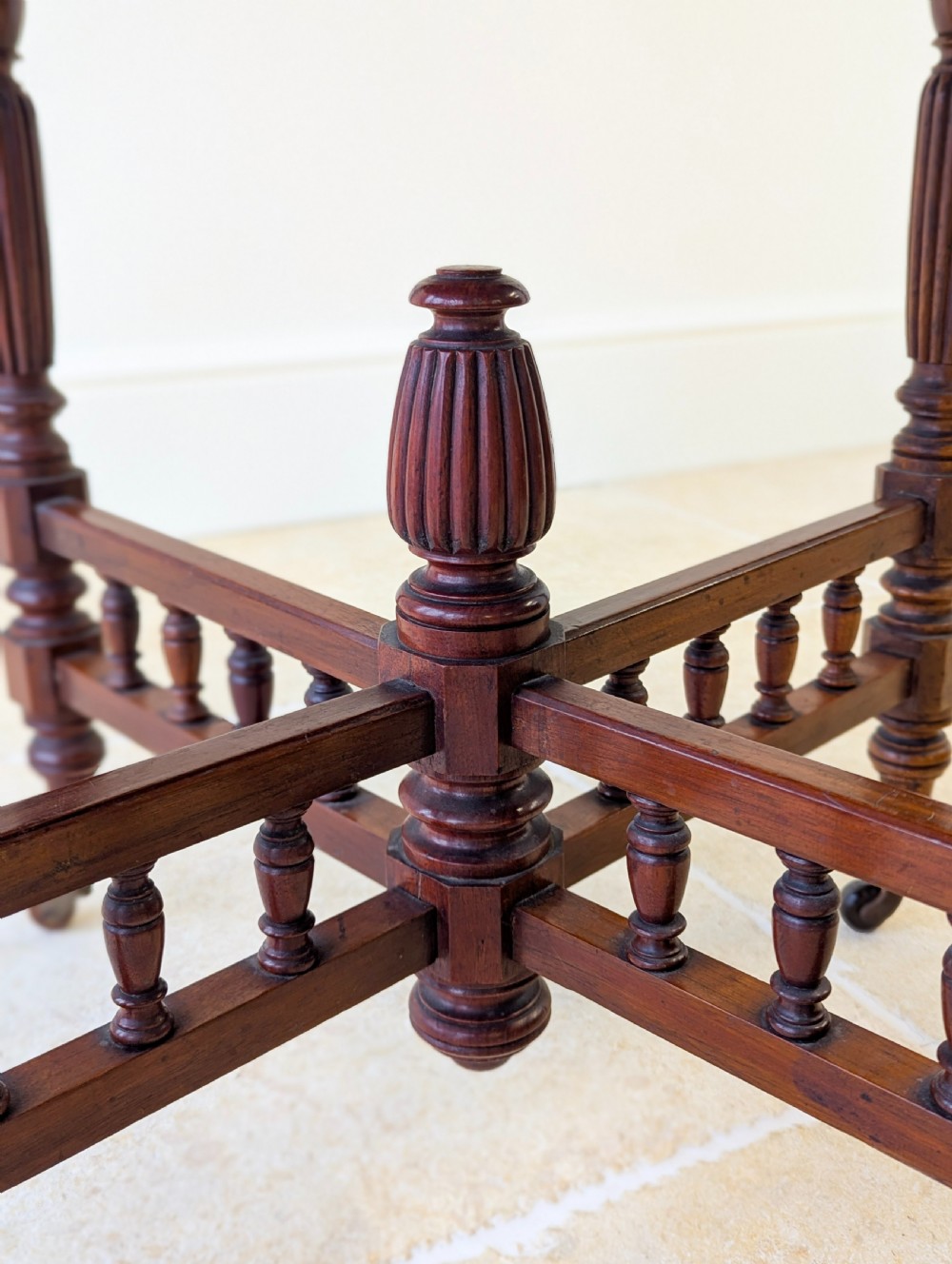 A late Victorian mahogany octagonal centre table featuring turned reeded legs, an intricate X-stretcher with baluster spindles, a central finial, and brass castors. View VII