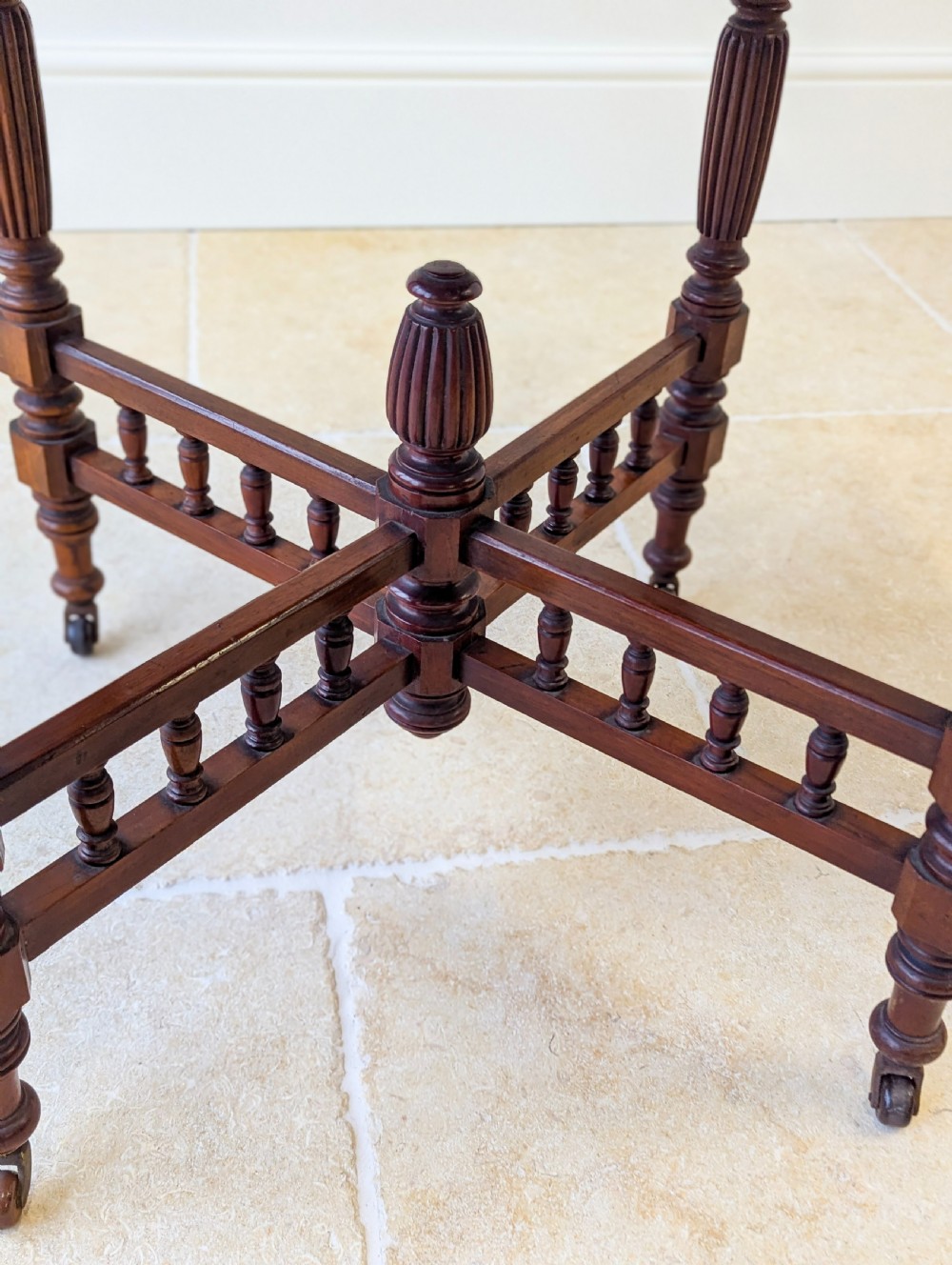 A late Victorian mahogany octagonal centre table featuring turned reeded legs, an intricate X-stretcher with baluster spindles, a central finial, and brass castors. View XIII