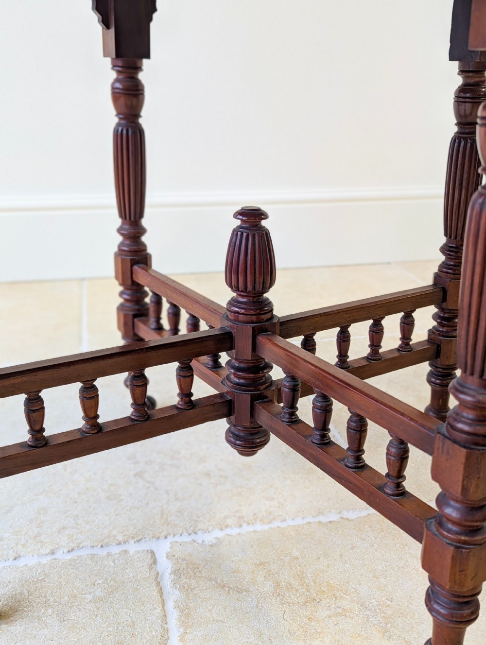 A late Victorian mahogany octagonal centre table featuring turned reeded legs, an intricate X-stretcher with baluster spindles, a central finial, and brass castors. View XVII