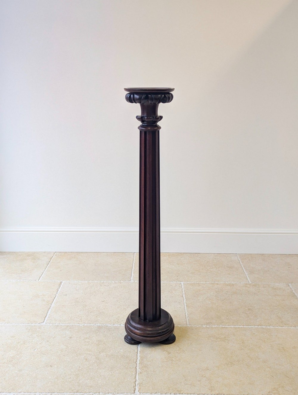 A tall Victorian dark mahogany torchere stand featuring a carved fluted column shaft, gadrooned top rim, and a circular moulded base.