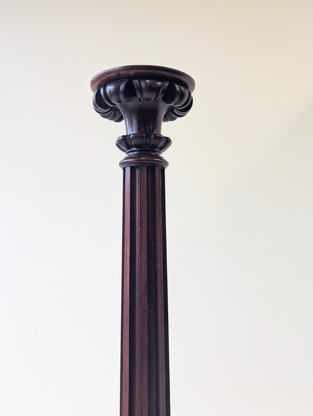 A tall Victorian dark mahogany torchere stand featuring a carved fluted column shaft, gadrooned top rim, and a circular moulded base. View II