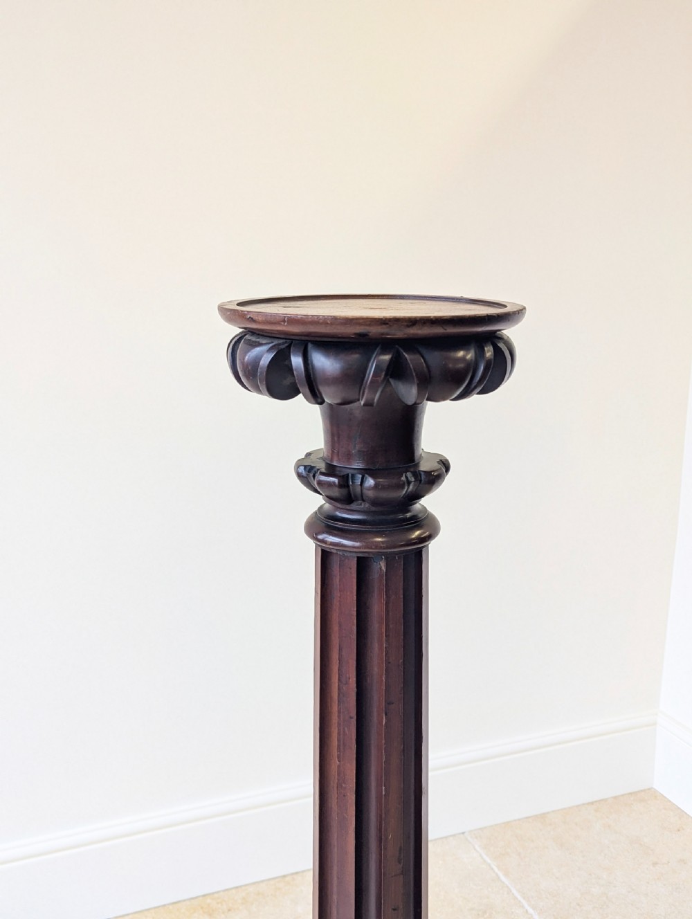 A tall Victorian dark mahogany torchere stand featuring a carved fluted column shaft, gadrooned top rim, and a circular moulded base. View IV