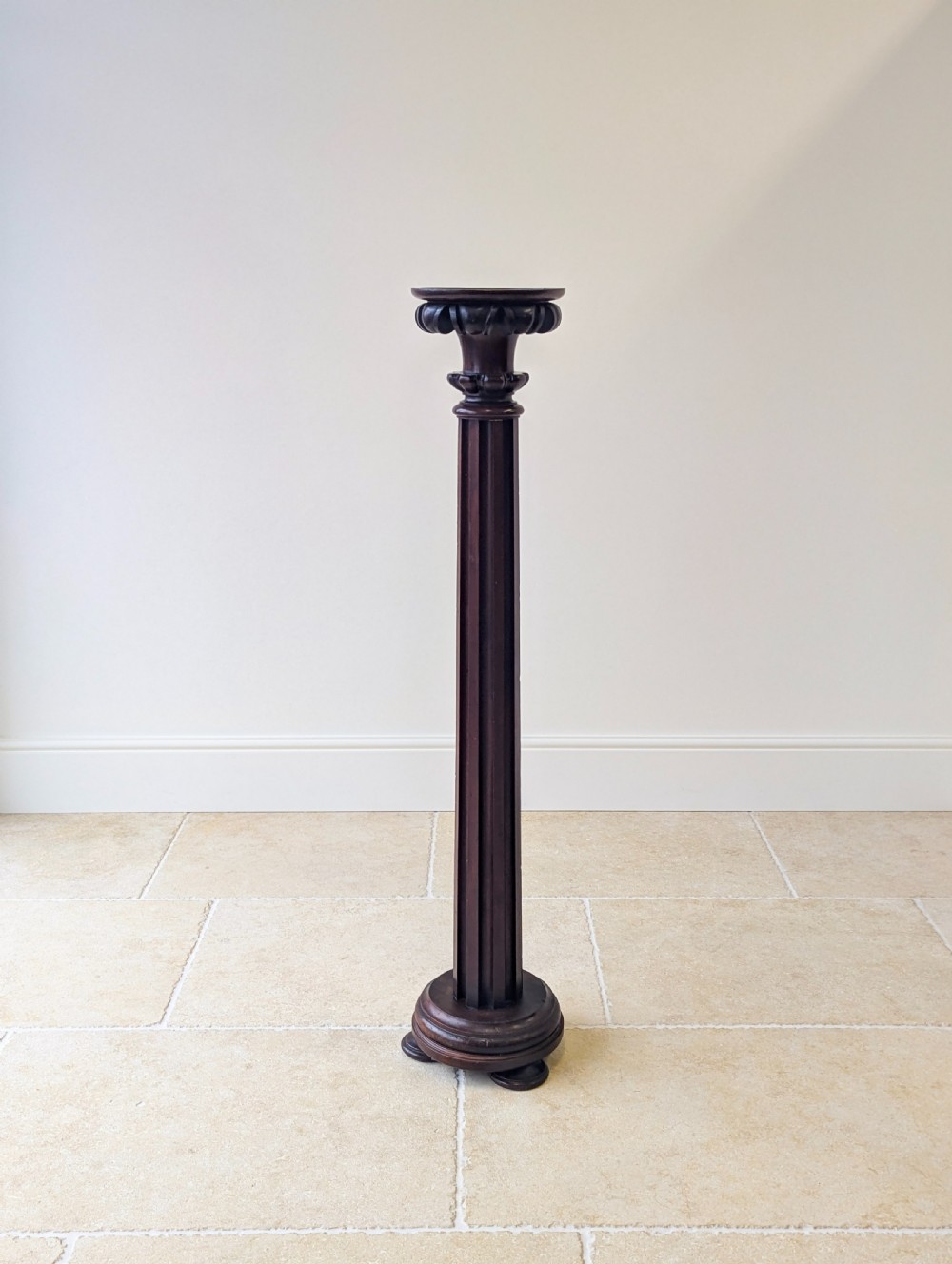 A tall Victorian dark mahogany torchere stand featuring a carved fluted column shaft, gadrooned top rim, and a circular moulded base. View V