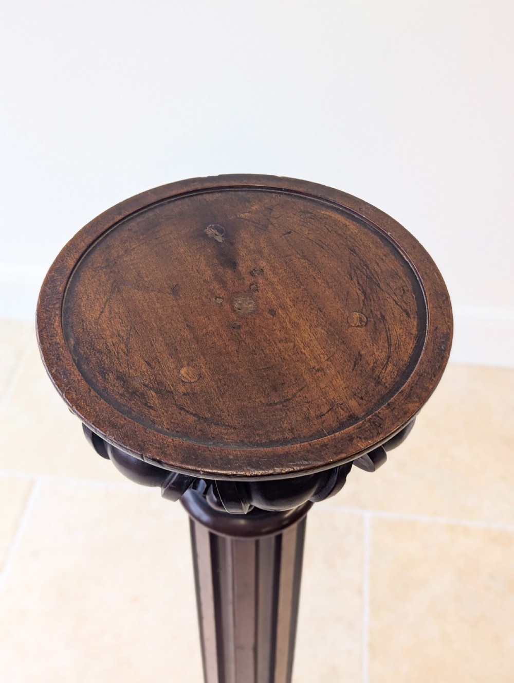 A tall Victorian dark mahogany torchere stand featuring a carved fluted column shaft, gadrooned top rim, and a circular moulded base. View VI